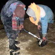 Ice Stupa team working with icy water sprinkler systems late at night.